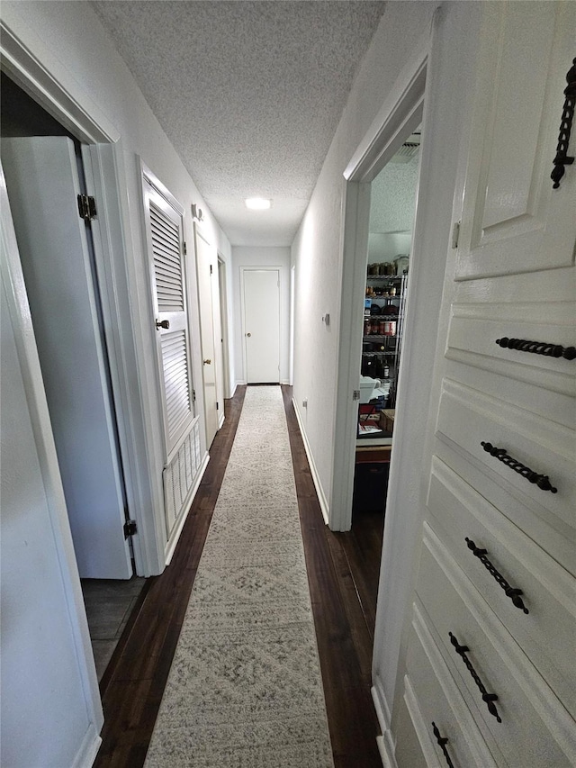 hallway featuring a textured ceiling and dark wood finished floors
