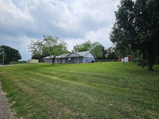 view of yard with an outbuilding, fence, and a storage shed