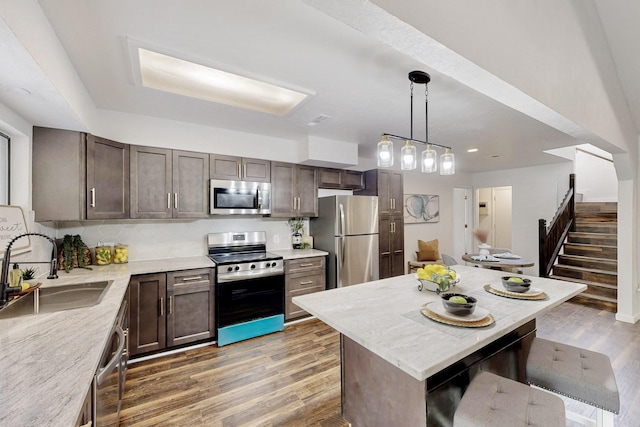 kitchen featuring light wood-type flooring, a sink, dark brown cabinetry, and stainless steel appliances