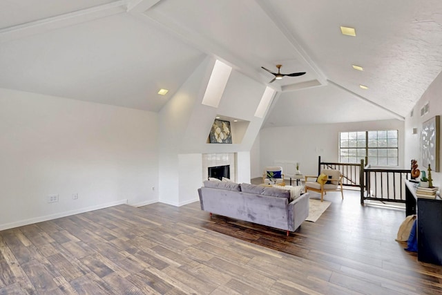 living room with vaulted ceiling with beams, baseboards, ceiling fan, and wood finished floors