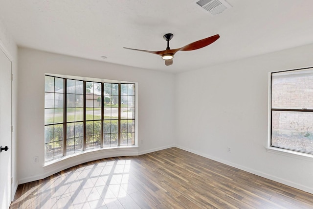 unfurnished room with visible vents, baseboards, ceiling fan, and wood finished floors