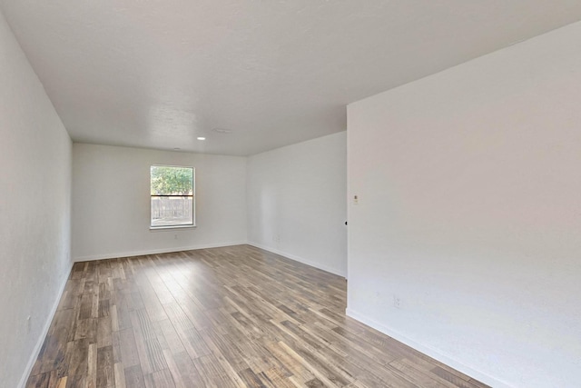 spare room with baseboards and wood finished floors