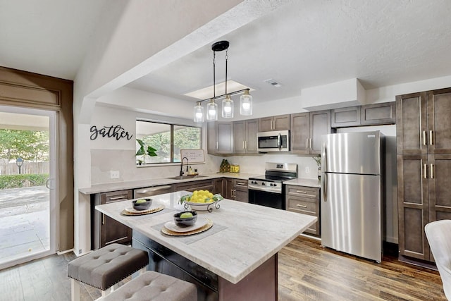 kitchen with a sink, a kitchen breakfast bar, a healthy amount of sunlight, and stainless steel appliances