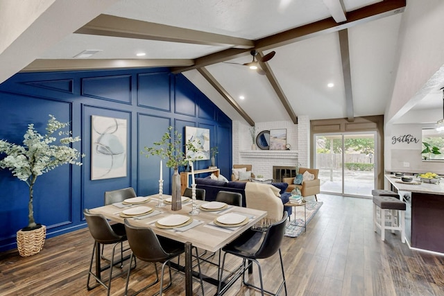dining area with a fireplace, dark wood finished floors, vaulted ceiling with beams, and a decorative wall