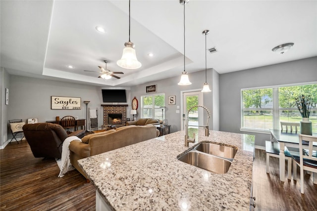 kitchen featuring plenty of natural light, a ceiling fan, a fireplace, a sink, and dark wood-style floors