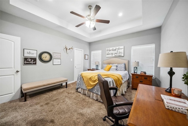 carpeted bedroom featuring ceiling fan and a tray ceiling