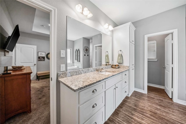 full bath featuring baseboards, wood finished floors, and vanity