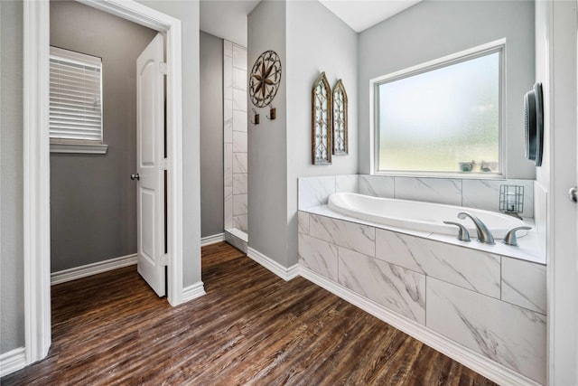 full bath featuring a garden tub, baseboards, walk in shower, and wood finished floors