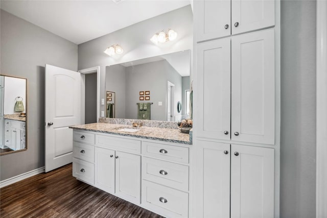 full bathroom with baseboards, wood finished floors, and vanity