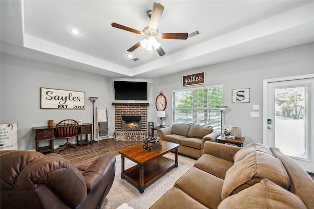 living room featuring ceiling fan, visible vents, a fireplace, wood finished floors, and recessed lighting
