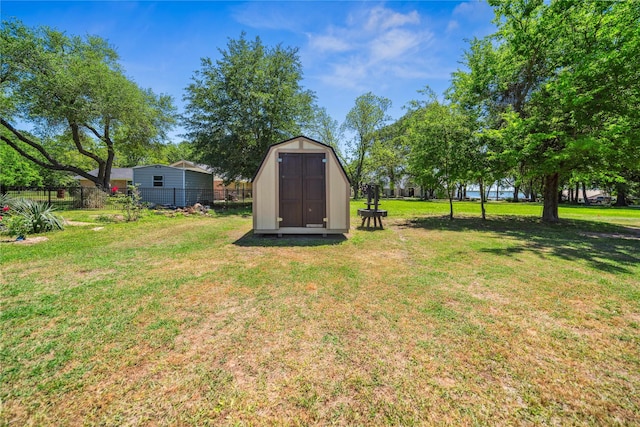 view of yard featuring an outdoor structure, fence, and a storage shed