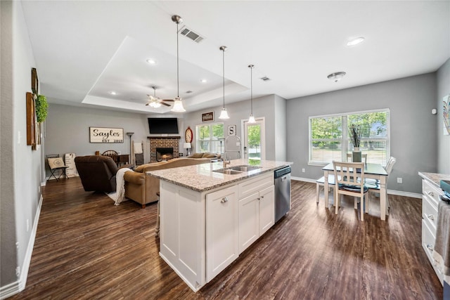 kitchen with a fireplace, a ceiling fan, baseboards, stainless steel dishwasher, and visible vents