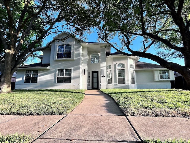 traditional-style house with stucco siding and a front lawn