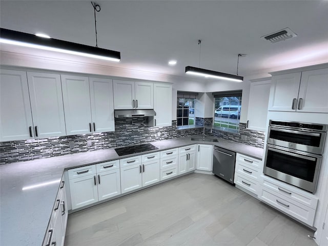 kitchen featuring a sink, stainless steel appliances, backsplash, under cabinet range hood, and visible vents