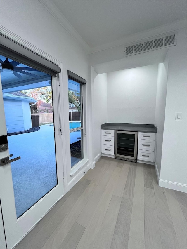 bar with visible vents, crown molding, baseboards, and wine cooler