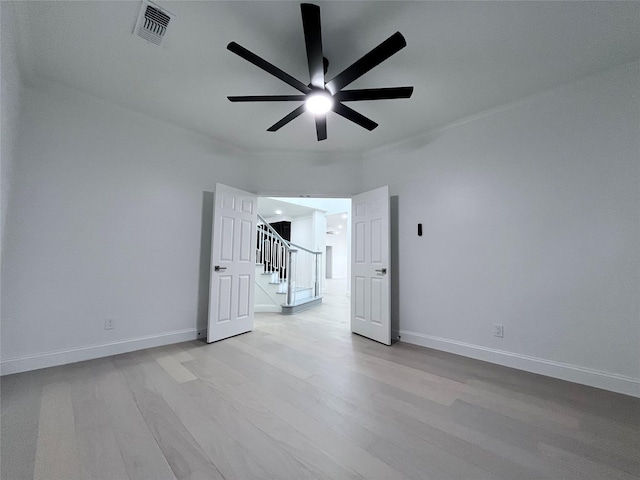 empty room with ceiling fan, visible vents, baseboards, light wood finished floors, and stairs