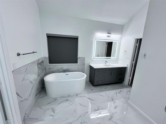 bathroom with a freestanding tub, baseboards, marble finish floor, and vanity