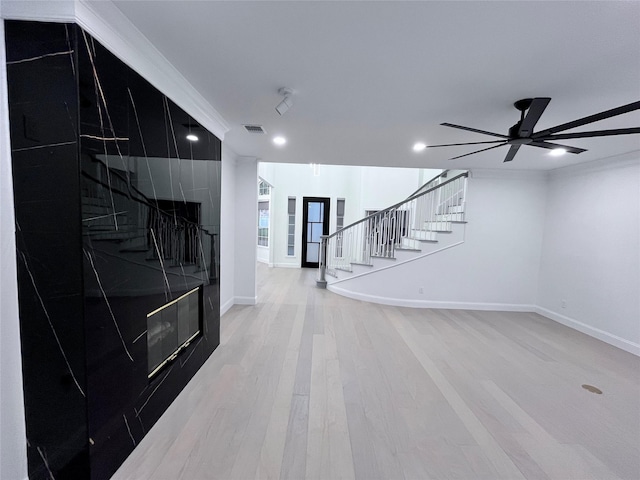 unfurnished living room with ceiling fan, visible vents, wood finished floors, stairway, and baseboards