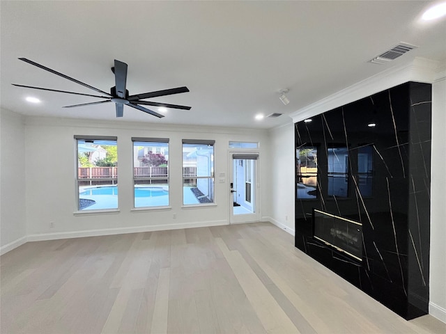 unfurnished room featuring visible vents, ornamental molding, baseboards, a ceiling fan, and light wood-style flooring