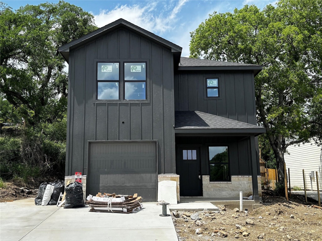 modern inspired farmhouse with a garage, a shingled roof, board and batten siding, and driveway