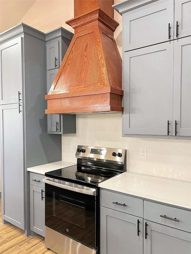 5008 San Marcos Dr, Granbury, TX 76048 - kitchen with stainless steel electric stove, custom range hood, gray cabinets, and light countertops