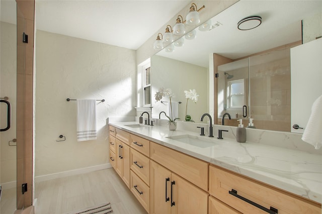 bathroom with a sink, baseboards, a stall shower, and double vanity