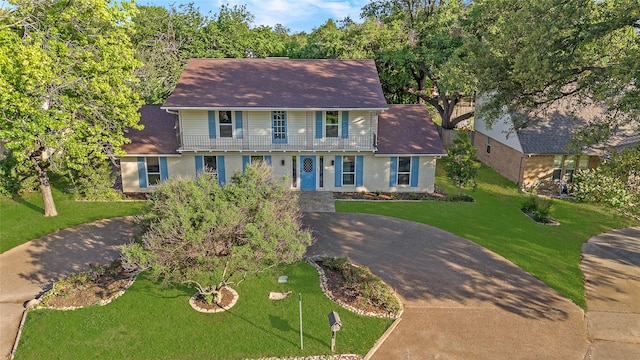 view of front of home with brick siding, a shingled roof, a front yard, and concrete driveway