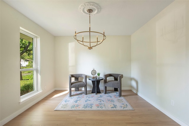 living area featuring baseboards, an inviting chandelier, and wood finished floors