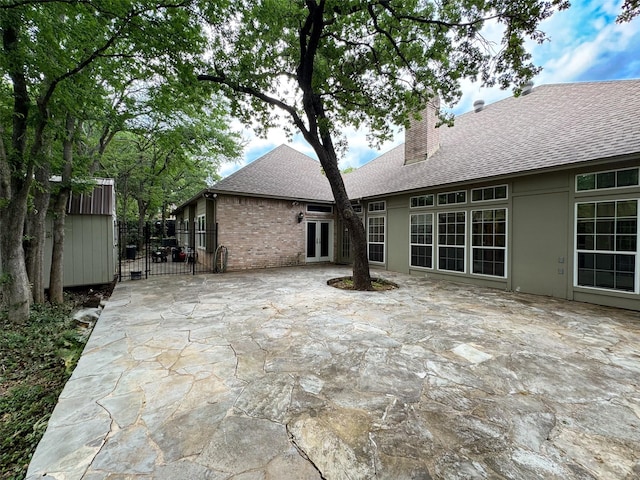 1520 Gatewood Dr, Denton, TX 76205 - rear view of house featuring a chimney, a shingled roof, a patio area, fence, and french doors
