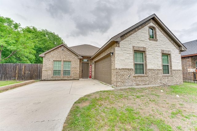 view of front of home featuring brick siding, fence, concrete driveway, an attached garage, and stone siding