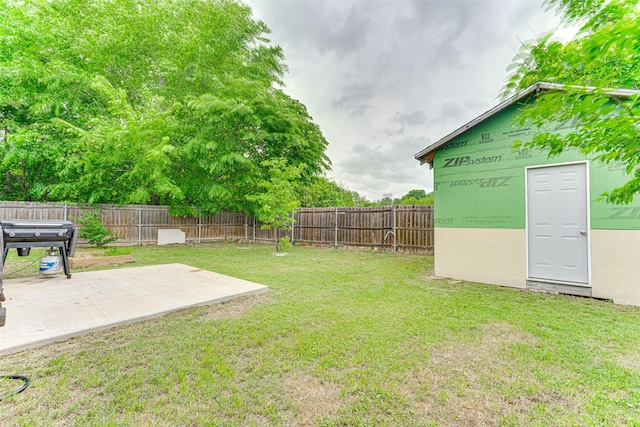 view of yard with an outdoor structure, a fenced backyard, and a patio area