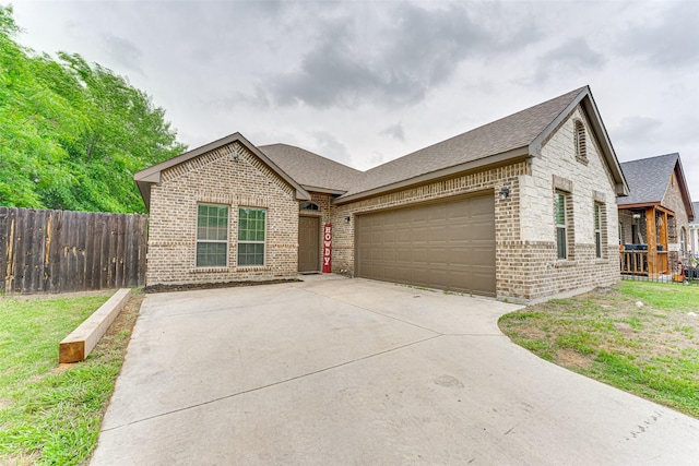 ranch-style home featuring a garage, fence, concrete driveway, and brick siding