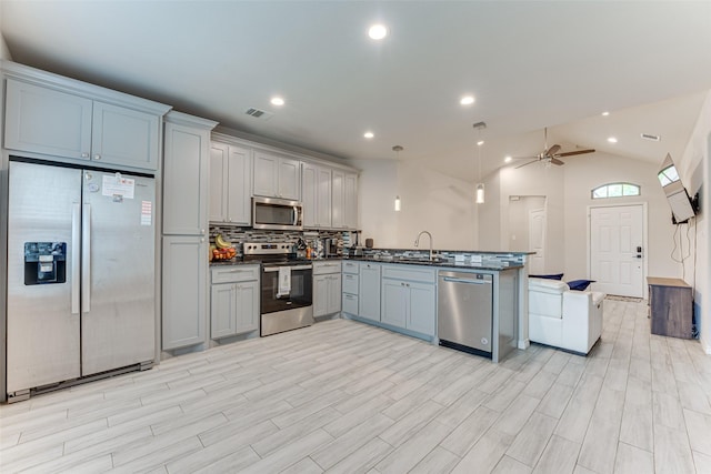 kitchen with decorative backsplash, a peninsula, open floor plan, a sink, and stainless steel appliances
