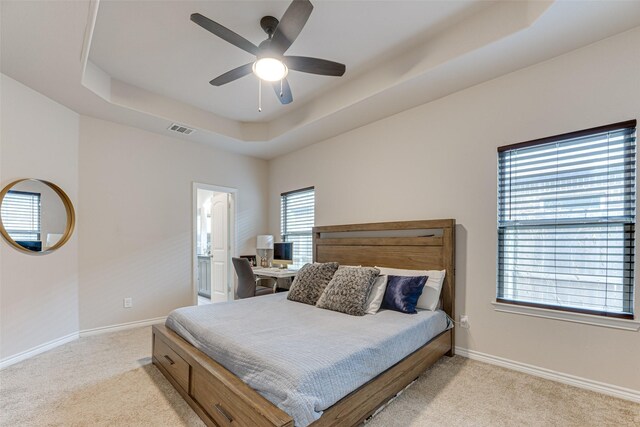 bedroom featuring visible vents, a raised ceiling, baseboards, and light colored carpet