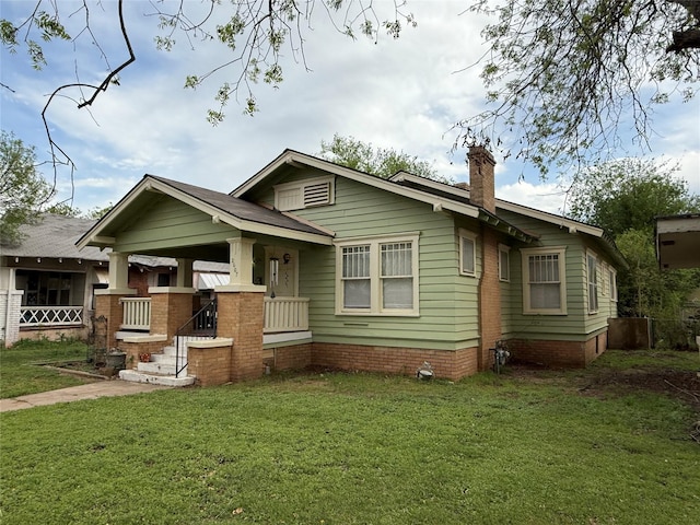 view of front of house featuring covered porch, a chimney, and a front lawn