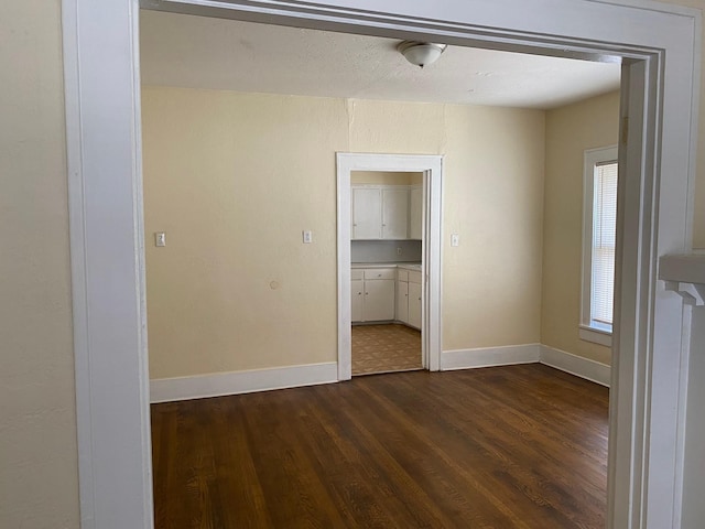unfurnished bedroom with baseboards and dark wood finished floors