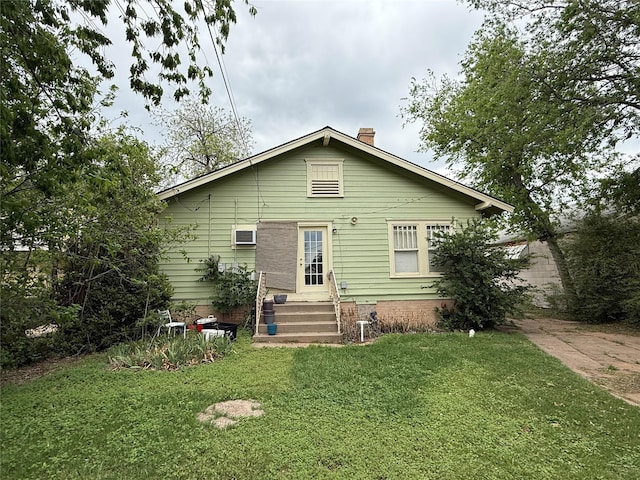 rear view of property with a yard, a chimney, and entry steps