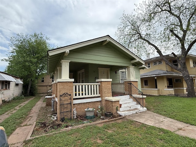 bungalow with covered porch and a front yard