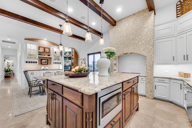 7242 Waters Edge Dr, The Colony, TX 75056 - kitchen with arched walkways, stainless steel microwave, backsplash, beamed ceiling, and a kitchen island