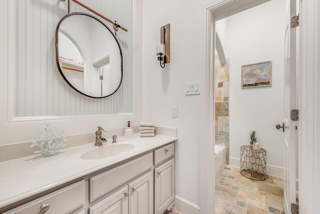 7242 Waters Edge Dr, The Colony, TX 75056 - bathroom featuring vanity, baseboards, a bathing tub, and stone tile flooring
