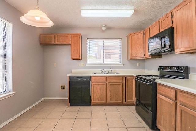 kitchen featuring light countertops, a textured ceiling, a sink, black appliances, and decorative light fixtures