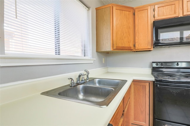 kitchen with a sink, black appliances, and light countertops