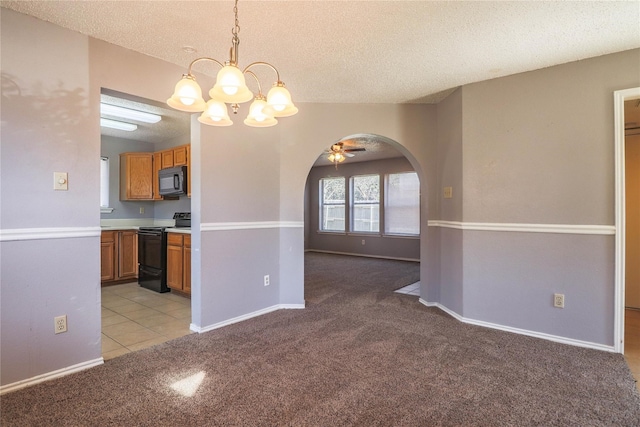unfurnished dining area featuring light carpet, baseboards, a textured ceiling, arched walkways, and ceiling fan with notable chandelier