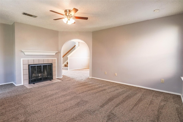 unfurnished living room with arched walkways, carpet flooring, a textured ceiling, and visible vents