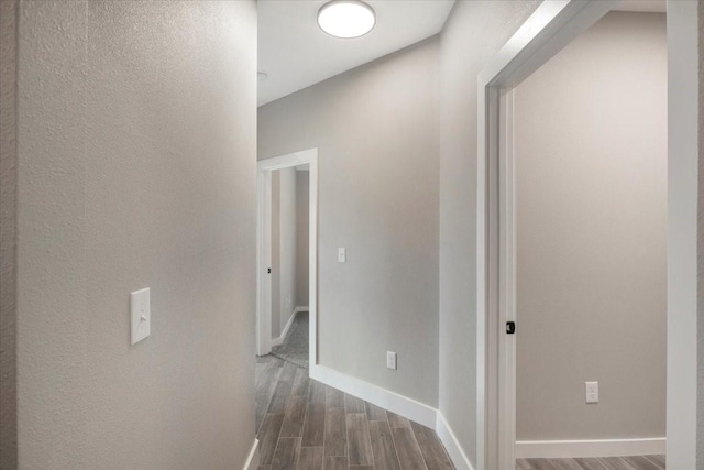 hallway featuring dark wood-type flooring and baseboards