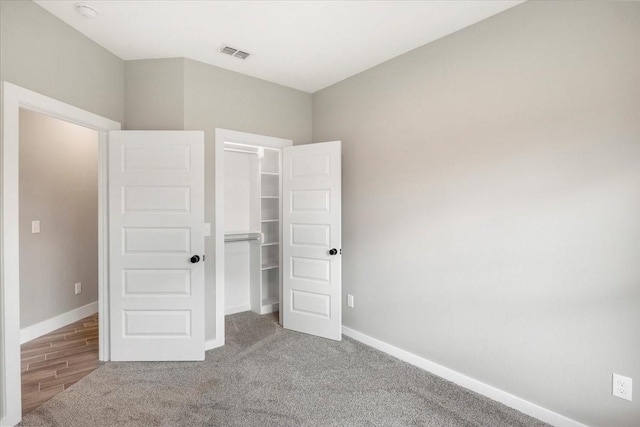 unfurnished bedroom with carpet flooring, baseboards, visible vents, and a spacious closet