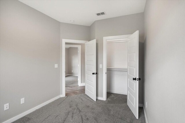 unfurnished bedroom with carpet floors, baseboards, visible vents, and a closet