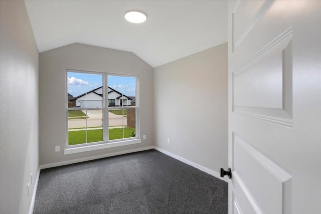 empty room featuring baseboards, dark carpet, and lofted ceiling