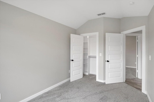 unfurnished bedroom with vaulted ceiling, visible vents, baseboards, and carpet
