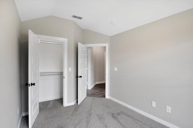 unfurnished bedroom with carpet, baseboards, vaulted ceiling, visible vents, and a closet